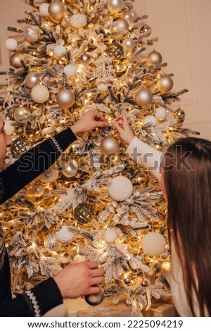 Vertical image lovely young romantic couple decorating Christmas tree kissing hugging home cosy interior atmosphere New Year holiday party celebrating concept winter garlands evening