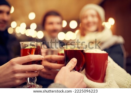 Close-up man's and woman's hands with hot cup mug of hot mulled wine. Happy holidays, national traditions, winter street fairs, Christmas concept. Festive decorations. Unfocused effect