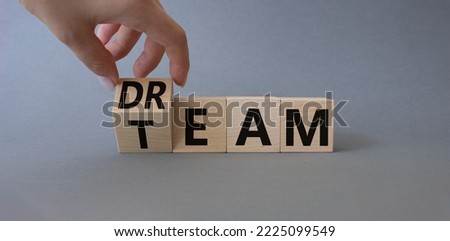 Dream Team symbol. Businessman hand turns wooden cube and changes word Team to Dream. Beautiful grey background. Business and Dream Team concept. Copy space.