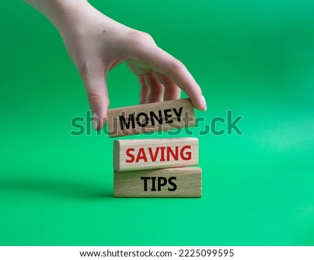 Money saving tips symbol. Concept words Money saving tips on wooden blocks. Beautiful green background. Businessman hand. Business and Money saving tips concept. Copy space.