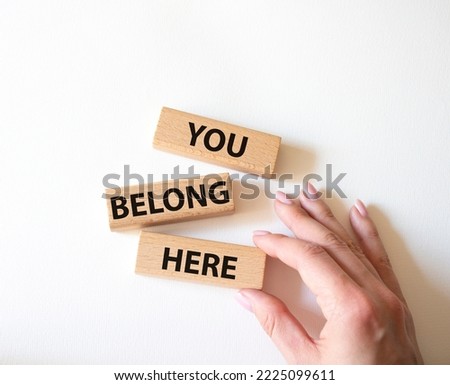You belong here symbol. Wooden blocks with words You belong here. Beautiful white background. Businessman hand. Business and You belong here concept. Copy space.