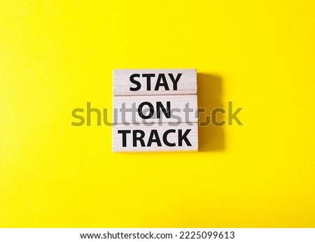 Stay on track symbol. Wooden blocks with words Stay on track. Beautiful yellow background. Businessman hand. Business and Stay on track concept. Copy space