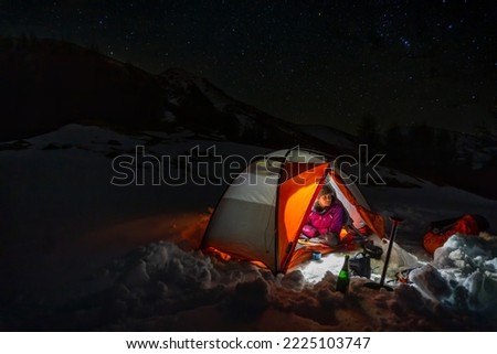 Woman camping in the snow under the stars