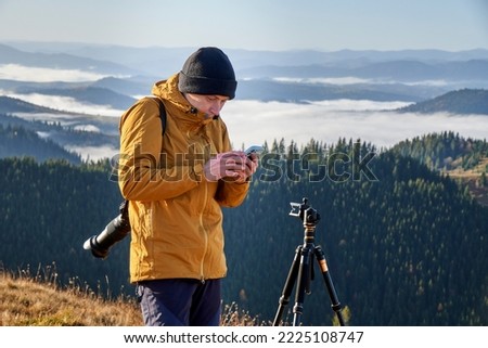 A young photographer taking picturesque photos using his cellphone. Landscape photography. Content maker. Pro photographer. The concept of travel and active lifestyle.  Time lapse on smartphone.    