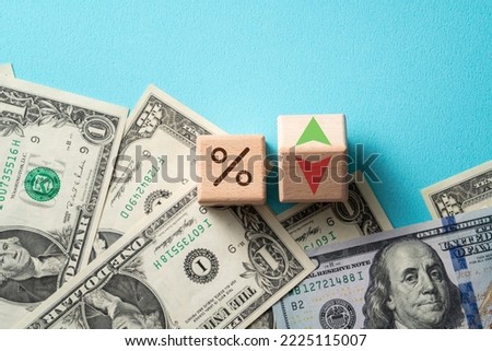 Wooden blocks with interest rate percent of bank with US dollars, financial world economy crisis design concept over blue table background. Royalty-Free Stock Photo #2225115007