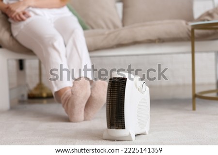 Modern electric fan heater on carpet in living room, closeup Royalty-Free Stock Photo #2225141359