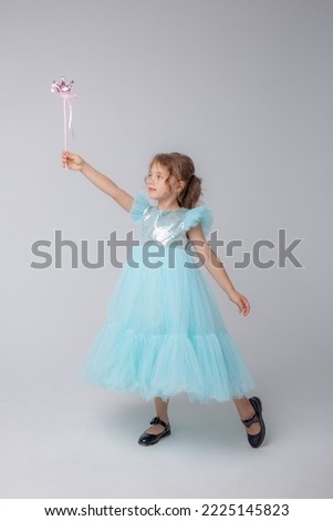 cute little girl in a beautiful dress holding a fairy magic wand on a white background