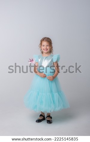 cute little girl in a beautiful dress holding a fairy magic wand on a white background