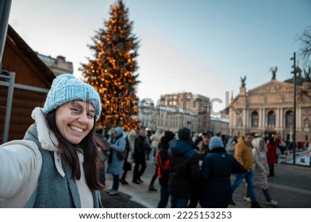 beautiful smiling women taking selfie picture at city square christmas tree on background copy space