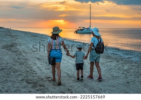 Two women hold the hands of a son, Family holidays on the sea coast, unconventional family, equality right, homosexuality lifestyle, lgbt at sunset Royalty-Free Stock Photo #2225157669