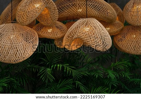 Group cluster of rattan lampshades in the tropical garden in evening lights on  Royalty-Free Stock Photo #2225169307