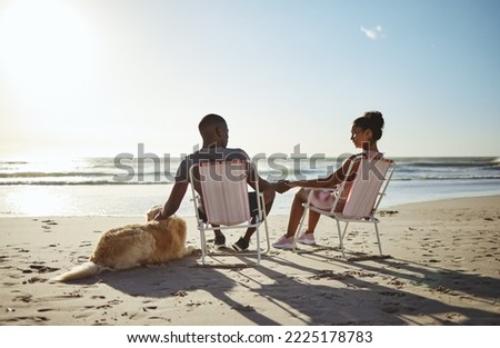 Black couple, dog and sunset beach while on chair to relax on vacation holding hands for love, care and trust by ocean for quality time. Pet with man and woman in healthy marriage on holiday by sea Royalty-Free Stock Photo #2225178783
