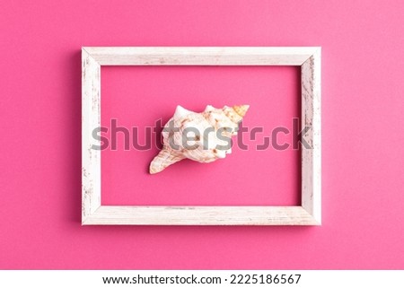 Minimalistic flat lay composition with vintage picture frame and seashell on bright pink background. Top view, summer time concept.
