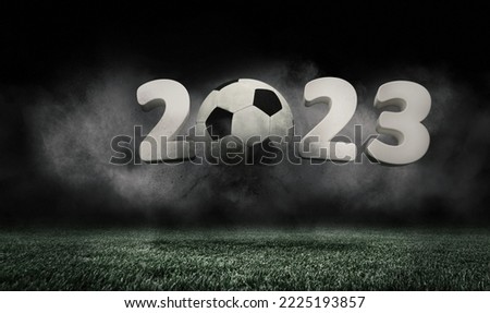 2023. Soccer ball jumping on green grass of football field isolated on dark background with smoke. Concept of sport, art, energy, power. Creative collage. World cup concept. Unfocus effect