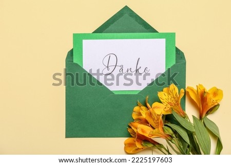 Card with word DANKE, envelope and flowers on beige background