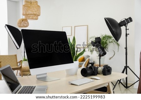 Photographer's workplace with computer, laptop and cameras in modern studio