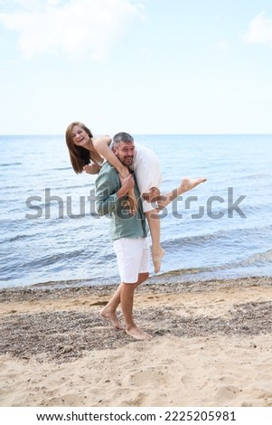 A vertical photoshoot of a Happy caucasian couple hugging and smiling on Baltic Sea sandy beach Royalty-Free Stock Photo #2225205981