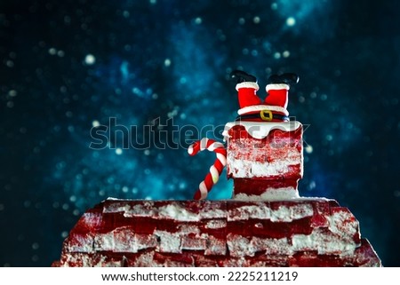 Santa's legs stick out of the chimney. Night, starry sky, Christmas background.