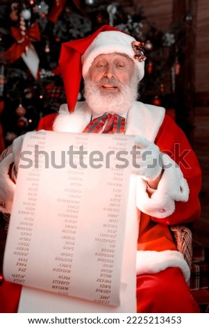 Santa Claus Nice List Scroll. Festive interior inside wooden house, New Year's cheerful mood Spirit of Christmas. Senior man with real white beard cosplay Father Christmas.