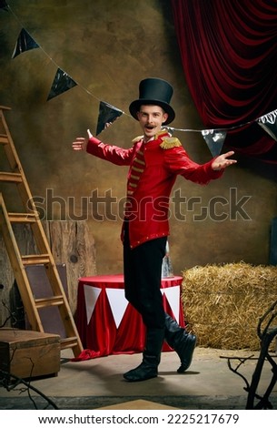 Showman. Vintage portrait of male retro circus entertainer expresses rejoice and announces start of show over dark retro circus backstage background. Concept of emotions, art, fashion, style Royalty-Free Stock Photo #2225217679