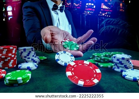 Gambling concept. Close up of casino bettor male hand throwing Сasino chips or Casino tokens at gambling club. Dice, poker cards, gambling man lucky guy spending time in games of chance at casino. Royalty-Free Stock Photo #2225222355