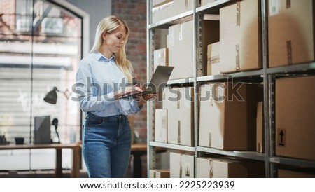 Female Inventory Manager Checks Stock, Writing in Clipboard App on Laptop Computer. Blond Woman Working in a Warehouse Storeroom with Rows of Shelves Full of Parcels, Packages Ready for Shipment.