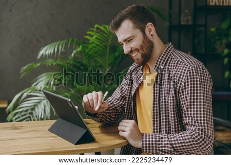 Young man he wear shirt graphic designer hold work use write draw stylus pc pen sit at table in coffee shop cafe relax rest in restaurant in free time indoors. Freelance mobile office business concept
