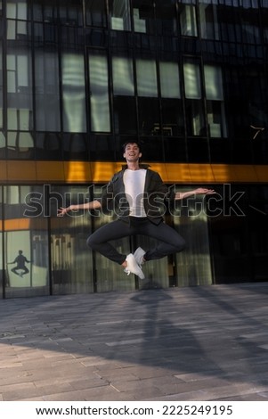young attractive dancer in casual cloth doing ballet jump on the urban background. Contemporary dance, modern choreography.