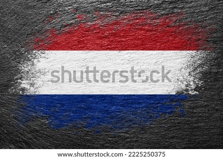 Flag of Netherlands. Flag is painted on a stone surface. Stone background. Black slate background. Creative background