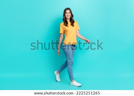 Full length photo of adorable pretty lady wear yellow t-shirt smiling walking isolated turquoise color background