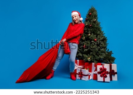 Full size photo of cute old lady hold bag to tree wear sweater cap jeans footwear isolated on blue background