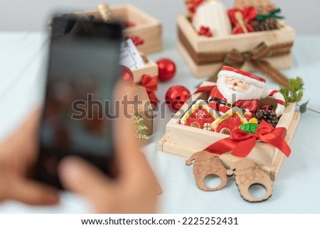 Selective focus on a table with christmas decoration objects into boxes while a person taking a photo