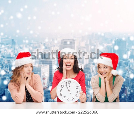 christmas, winter, holidays, time and people concept - smiling women in santa helper hats with clock over snowy city background