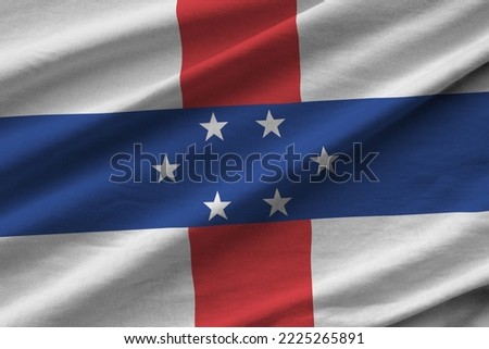 Netherlands Antilles flag with big folds waving close up under the studio light indoors. The official symbols and colors in fabric banner