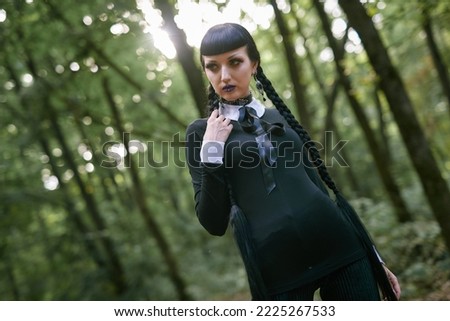 Dark goth girl standing in the forest, portrait of a wiccan witch performing magic Royalty-Free Stock Photo #2225267533
