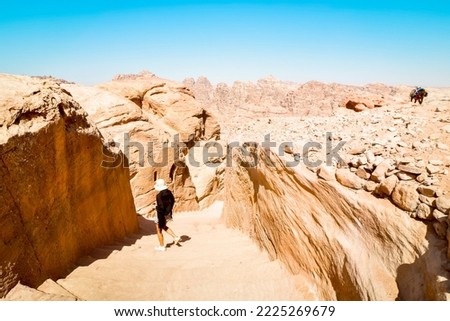 Caucasian tourist girl stand on staircase to A'dir monastery on mountain in Petra lost city historical landmark