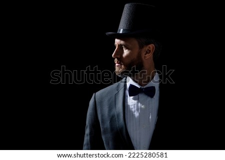 photo of tuxedo presenter in cylinder hat. tuxedo presenter isolated on black background.