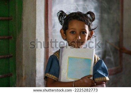 School girl holding book standing at school Royalty-Free Stock Photo #2225282773