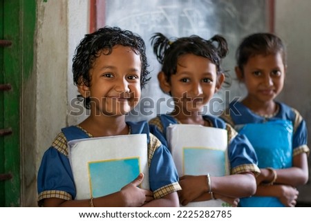 Three School Children's holding books standing at school Royalty-Free Stock Photo #2225282785