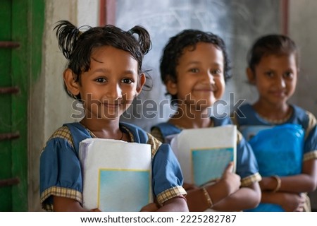 Three School Children's holding books standing at school Royalty-Free Stock Photo #2225282787