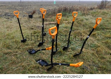 Shallow depth of field (selective focus) image with shovels during an autumn tree planting on a November cold and rainy day.