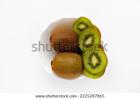 Fresh and juicy kiwi fruit, chopped and whole on a white plate. Delicious fruits and pieces of green kiwi.Healthy vegan food. Healthy eating. Green natural background. Vegetarian food.