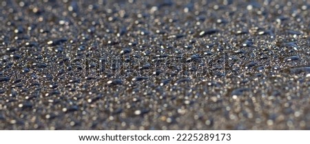 Large and small drops of water on a dark gray background.