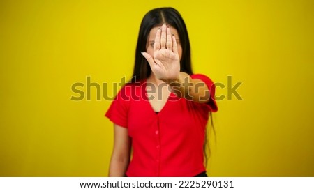 Portrait of a Asian beautiful young woman unhappy or confident standing say no, studio shot isolated yellow background, Indian female pose saying reject gesture with copy space