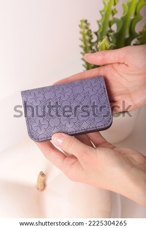 leather cardholder in human hands closeup photo on white wall background