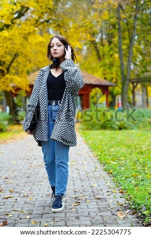 young girl listens to music in the park