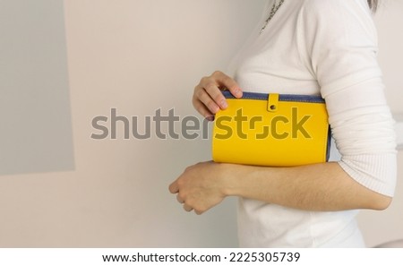 yellow lacquered leather purse close up photo in human hand