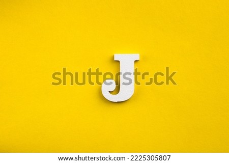Alphabet letter J - White wood letter on yellow colored background