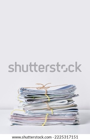 a stack of newspapers tied with twine rope on a white background stock photo - premium, high resolution, code no 1