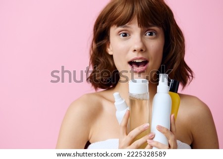 a close horizontal photo on a pink background of a shocked, surprised woman, holding various care products in her hands and looking at the camera with her mouth wide open. Skin care topics